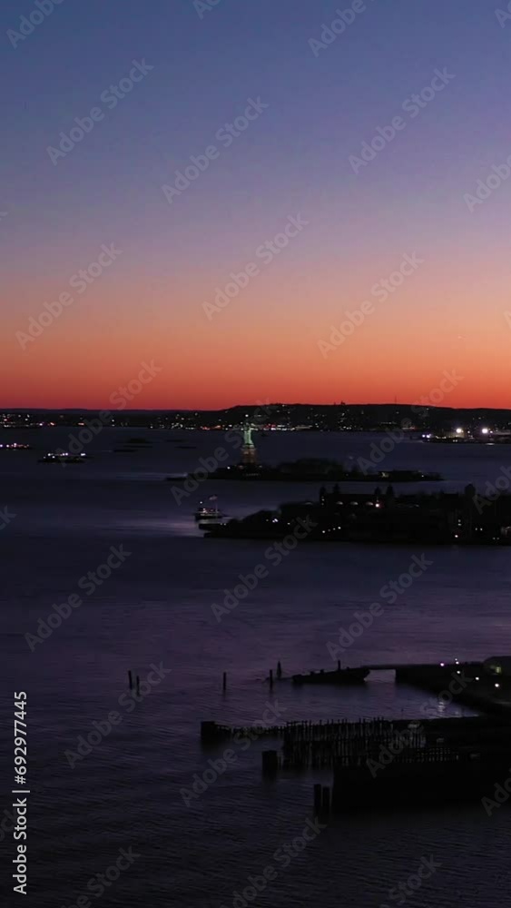 Illuminated Statue of Liberty and Verrazzano Bridge at Evening Twilight. Blue Hour. Aerial View. New York City, USA. Vertical Video Illuminated Statue of Liberty and Verrazzano Bridge at Evening Twilight. Blue Hour. Aerial View. New York City, USA. Vertical Video