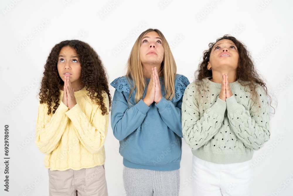 multi racial group of girl friends begging and praying with hands together with hope expression on face very emotional and worried. Please God multi racial group of girl friends begging and praying with hands together with hope expression on face very emotional and worried. Please God