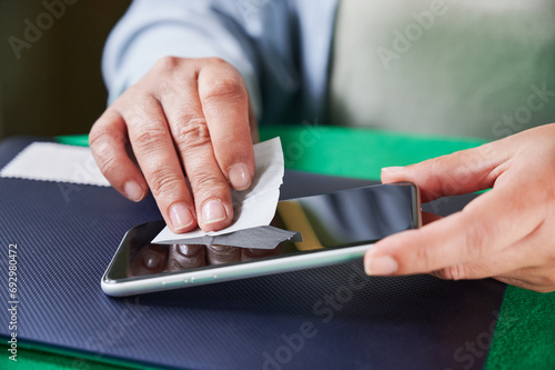 Unrecognizable woman using a wet wipe to clean the mobile phone screen before installing a new anti-scratch protector photo
