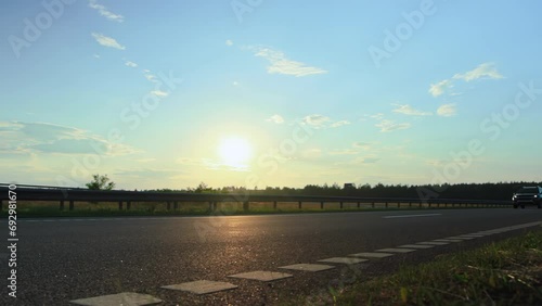 2 hatchback cars driving fast on the highway at sunset, two lane roadway. Traffic barrier guard rail along throughway. Compliance with speed limits on motorway countryside photo