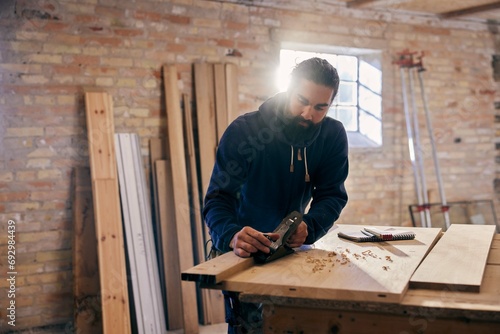 Woodworker planing a plank in his workshop photo