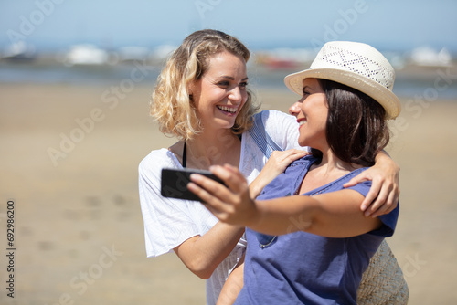 young female friends on vacation taking selfie on the beach