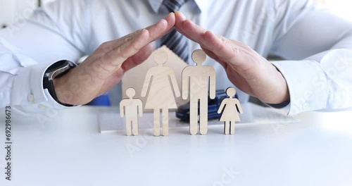Male hands over a wooden family model, close-up, slow motion. Property and health insurance photo
