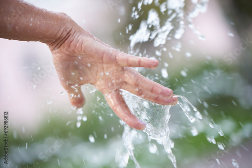 A woman's hand under splashes of water from a fountain.