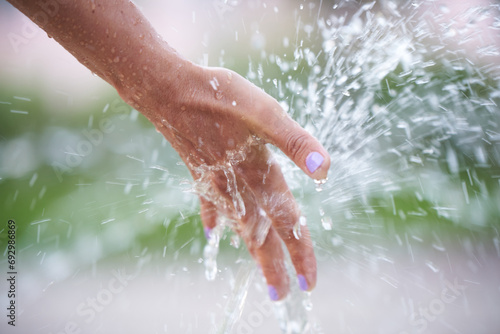 A woman's hand under splashes of water from a fountain.