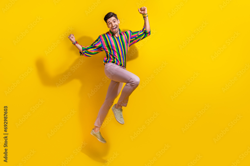 Full body photo of young boyfriend wearing stylish vintage old school garment raised fists up jumping isolated on yellow color background