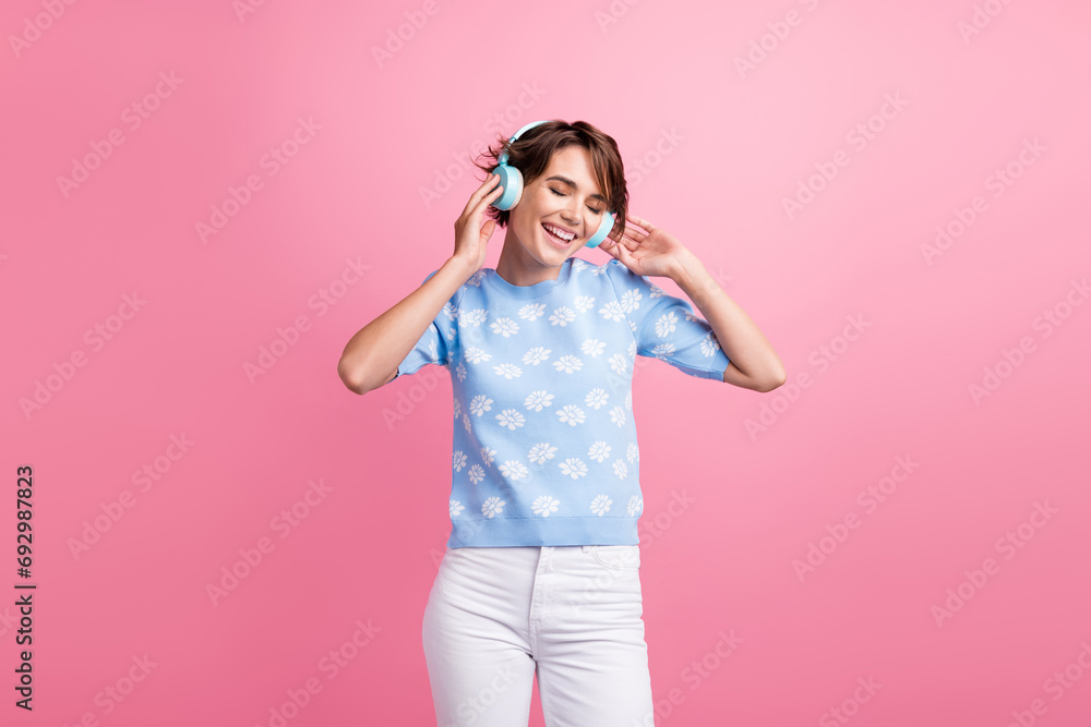Photo of positive lovely girl hands touch headphones listen favorite music isolated on pink color background Photo of positive lovely girl hands touch headphones listen favorite music isolated on pink color background