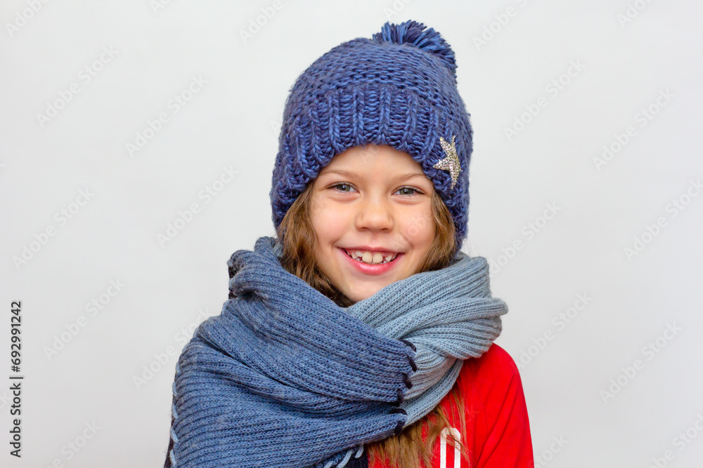 Portrait of caucasian happy smiling little girl in red with blue hat and scarf of 6 7 years old looking at camera Portrait of caucasian happy smiling little girl in red with blue hat and scarf of 6 7 years old looking at camera