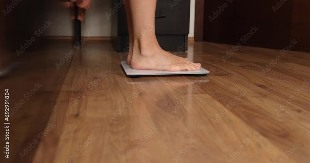 A person is weighed after sleep, feet on the floor close-up. Joy of weight loss, weight control, measurement A person is weighed after sleep, feet on the floor close-up. Joy of weight loss, weight control, measurement