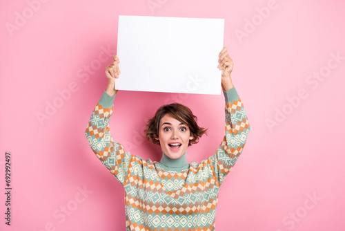 Photo of funky young lady astonished holding paper small placard mockup promoting wishlist shopping isolated on pink color background photo