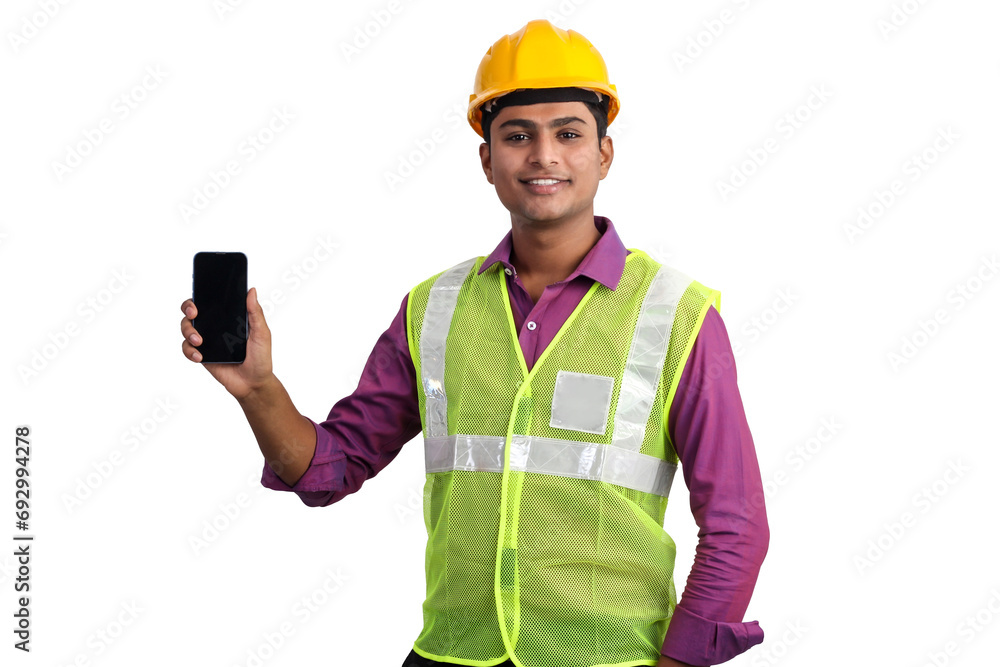 Indian male architect wearing yellow helmet and safety jacket showing smartphone in studio. Indian male architect wearing yellow helmet and safety jacket showing smartphone in studio.