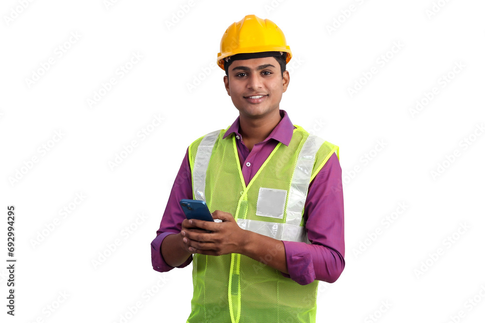 Fototapeta premium Indian male architect wearing yellow helmet and safety jacket posing with smartphone in studio.