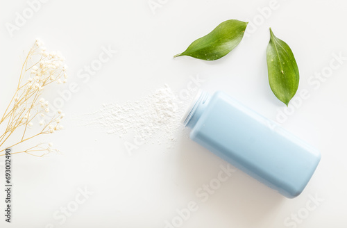 Baby talcum powder container with green leaves  top view. Child care concept