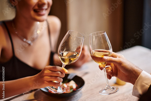 happy couple clinking glasses of white wine during date on Valentines day, romantic dinner photo