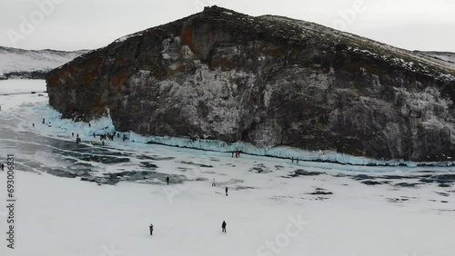 Tourists admire icicles on the huge rocks of Olkhon Island. Winter trip on the frozen lake Baikal.