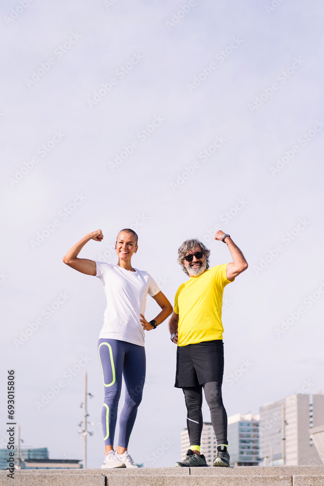 senior man and his personal trainer posing flexing muscle and smiling happy looking at camera, concept of active and healthy lifestyle in middle age, copy space for text senior man and his personal trainer posing flexing muscle and smiling happy looking at camera, concept of active and healthy lifestyle in middle age, copy space for text