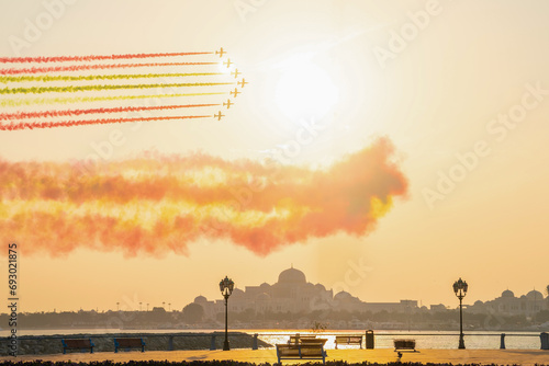 Air show with seven jet planes flying over presidential palace in Abu Dhabi paint the sky with flag colour in sunset. High quality photo photo