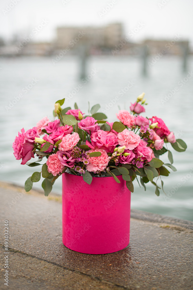 Bouquet of roses and carnations in a gift box stands on a curb, close up