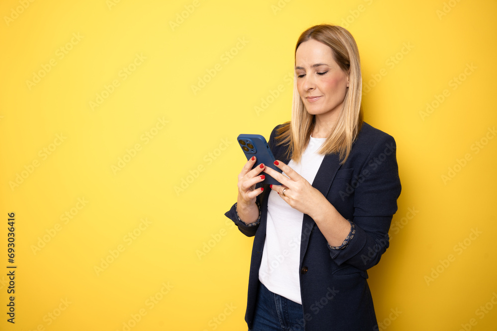 Young business woman using smartphone on yellow studio background Young business woman using smartphone on yellow studio background