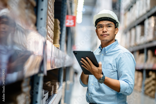Businessman or supervisor uses a digital tablet to check the stock inventory in furniture large warehouses, a Smart warehouse management system, supply chain and logistic network technology concept. © sirichai