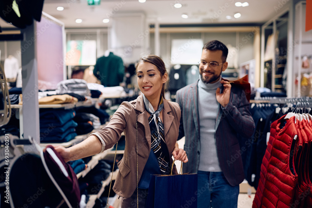 Young woman and her boyfriend shopping at clothing store. - obrazy, fototapety, plakaty 