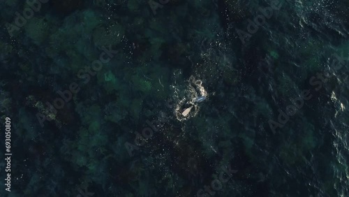Aerial footage (top view) of diver with orange swimming buoy (bag) on the ocean on sunset. Diver in wetsuit swimming in the ocean.