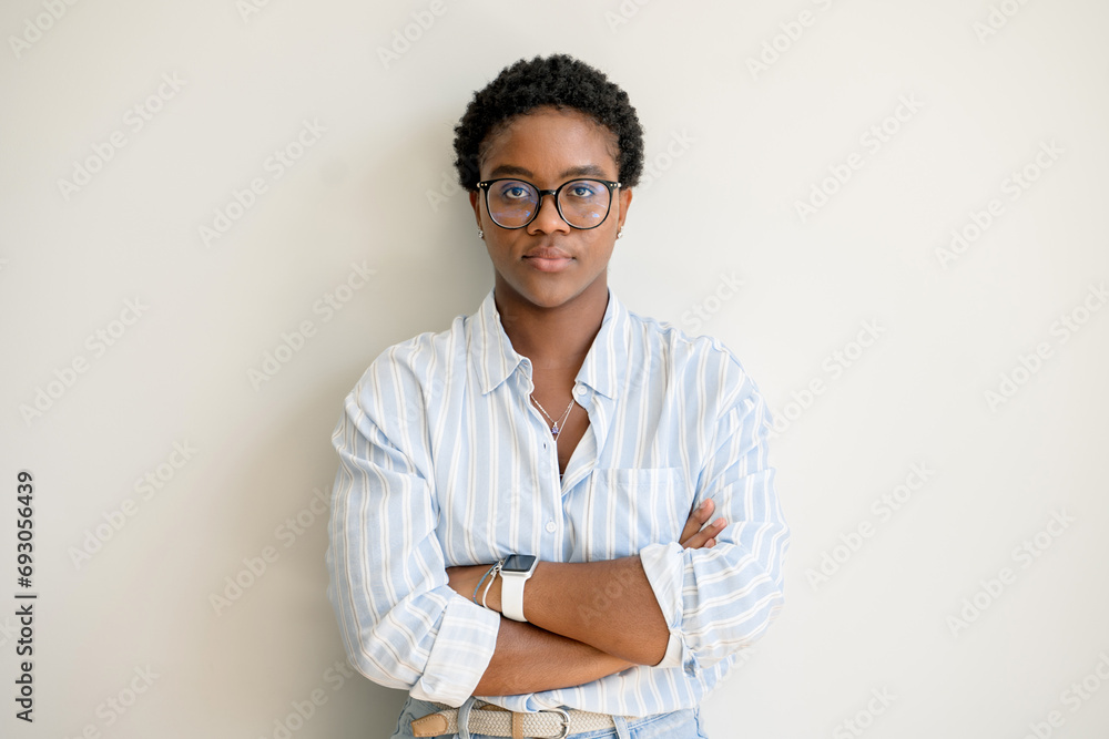 Portrait of a serious young confident African American female entrepreneur standing with arms folded isolated on white and looking at camera, intelligent smart businesswoman posing with arms crossed Portrait of a serious young confident African American female entrepreneur standing with arms folded isolated on white and looking at camera, intelligent smart businesswoman posing with arms crossed