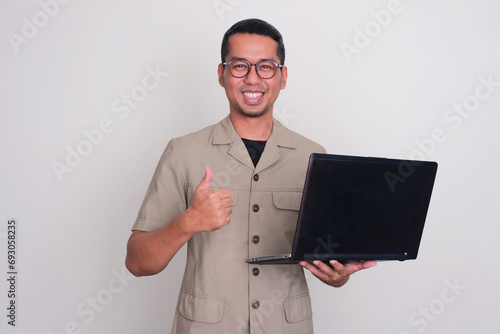 Indonesia government worker smiling and giving thumb up while holding a laptop photo