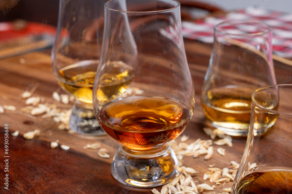 Tasting of different Scotch whiskies strong alcoholic drinks, drum of whiskey and colorful Scotch tartan on background close up Tasting of different Scotch whiskies strong alcoholic drinks, drum of whiskey and colorful Scotch tartan on background close up