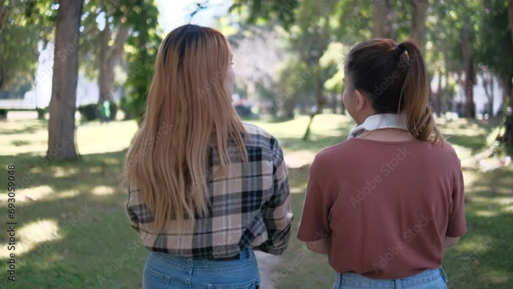 Two happy students walking and talking each other in a campus at sunset with a warm light Two happy students walking and talking each other in a campus at sunset with a warm light