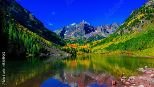 Tranquil forest with mountain range reflecting in calm lake