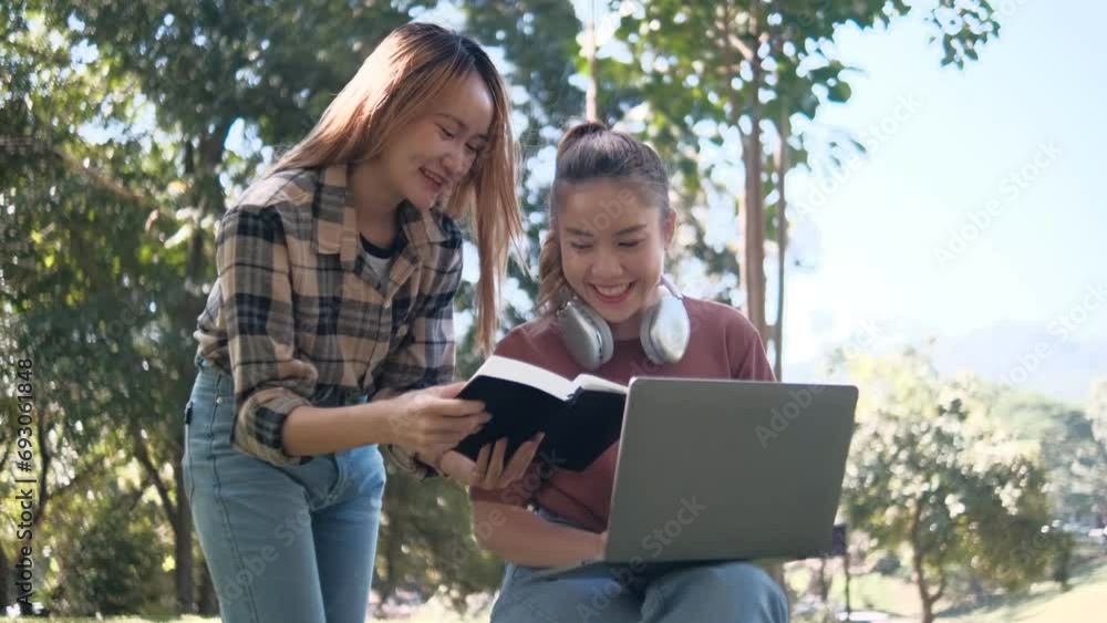 Two female students working and learning together for exams sitting on University campus grass Two female students working and learning together for exams sitting on University campus grass