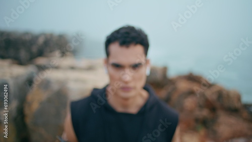 Portrait brunette man posing at ocean cliff view. Zoom in handsome athletic guy