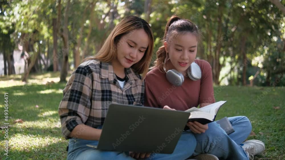 Two female students working and learning together for exams sitting on University campus grass Two female students working and learning together for exams sitting on University campus grass
