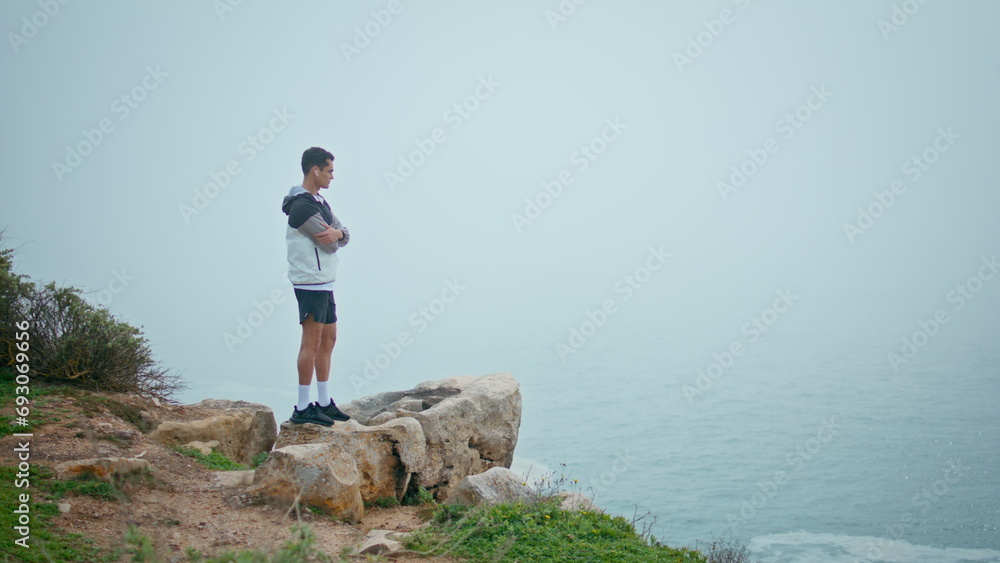 Calm guy looking ocean in fog morning. Thoughtful sportsman rest after workout