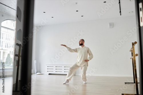 Wide angle view at adult male trainer warming up for qigong class while standing in modern studio © Seventyfour