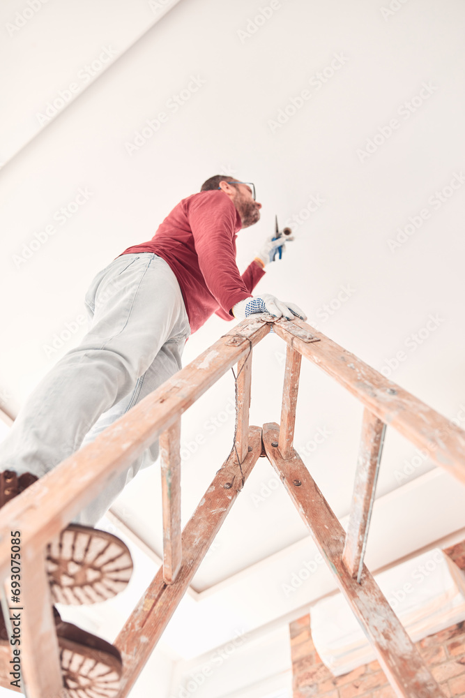 Handyman electrician with ladders working in a new home interior.