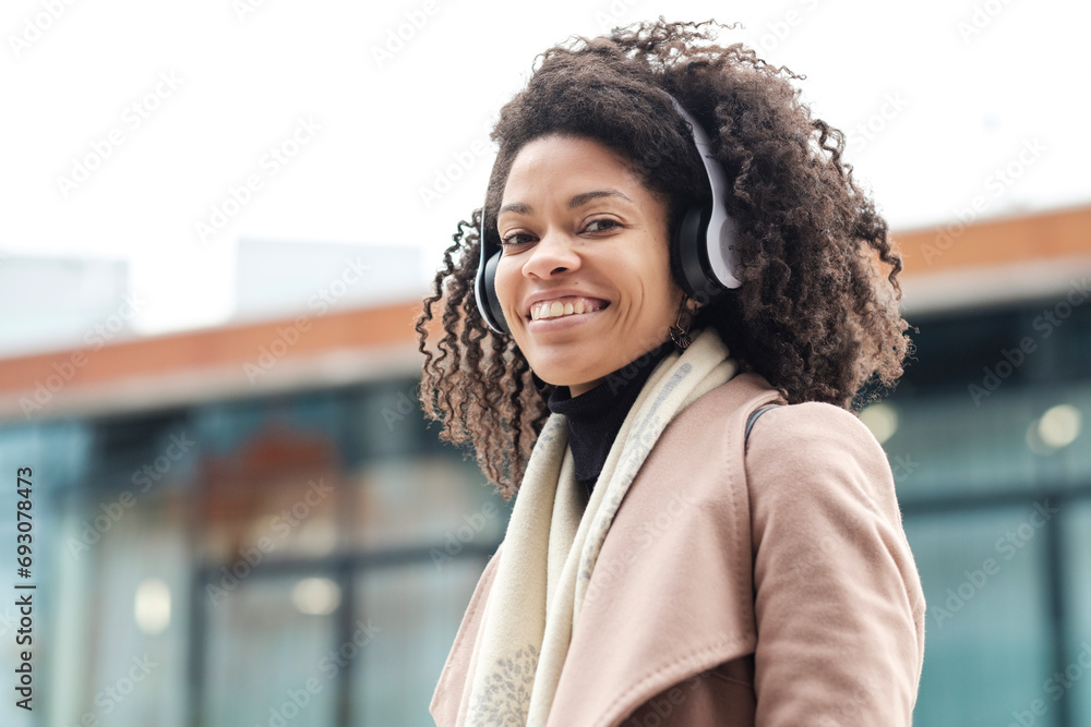 Portrait of friendly black woman using headphones and looking at camera. - obrazy, fototapety, plakaty 