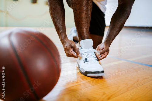 Close up man tying basketball shoes at indoor gym photo
