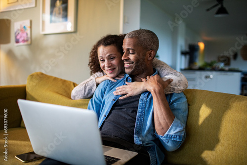 Happy couple using laptop together at home photo