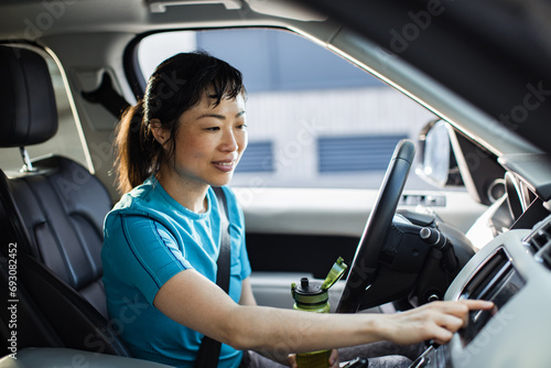 Asian Woman Hydrating While Sitting in Her Car photo