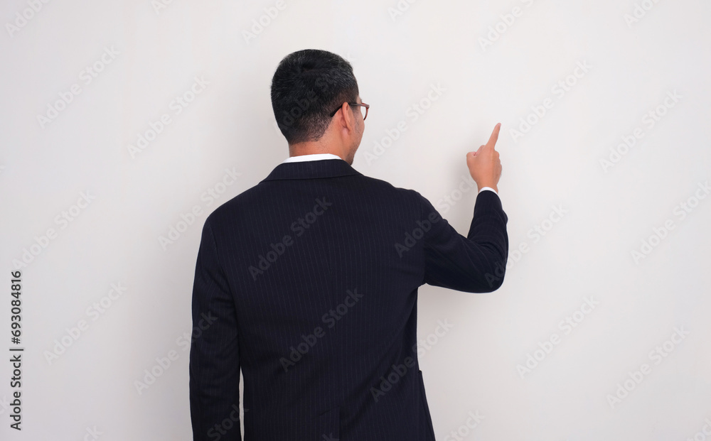 Back view of businessman pointing to white space Back view of businessman pointing to white space