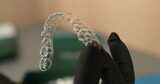 Aligners in the hands of the doctor, rubber gloves hold modern tools for teeth correction.