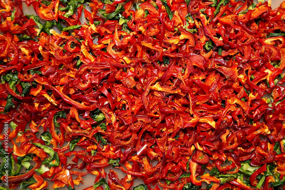 Fototapeta premium a lot of dried red and green bell peppers in an electric dryer. view from above. red and green food background