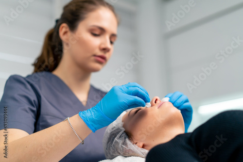 portrait of a beautician doctor cleaning a client's skin with a cotton sponge before starting a beauty and health procedure