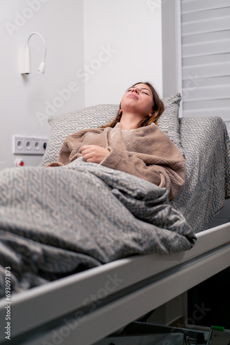 a sick patient in a hospital is lying on a bed sneezing and suffering from a runny nose cough and headaches photo