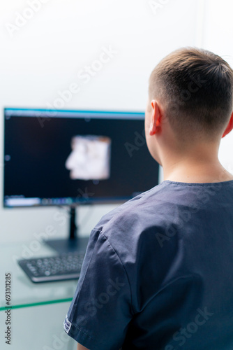 a radiologist doctor looks at a screen showing a 3D image of a nose scan to determine the results of plastic surgery in a clinic