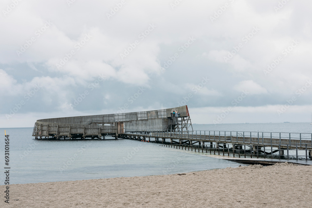 Kastrup Sobad, Copenhagen, Denmark, A round structure representing a swimming pool in the sea, which can be accessed via a walkway leading from the beach. Kastrup Sobad, Copenhagen, Denmark, A round structure representing a swimming pool in the sea, which can be accessed via a walkway leading from the beach.