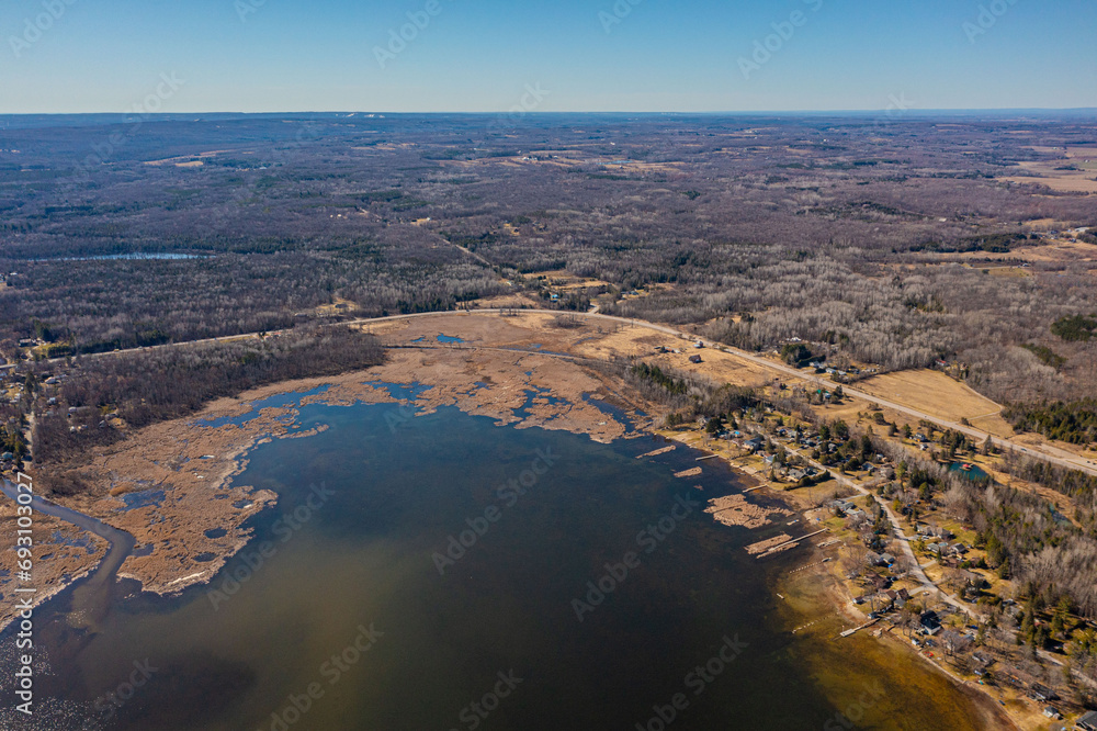 Expansive aerial views over Tay Township, Simcoe County, Ontario, capture the grandeur of the Canadian landscape. From the shimmering waters reflecting the sun's glare to the sprawling patches.