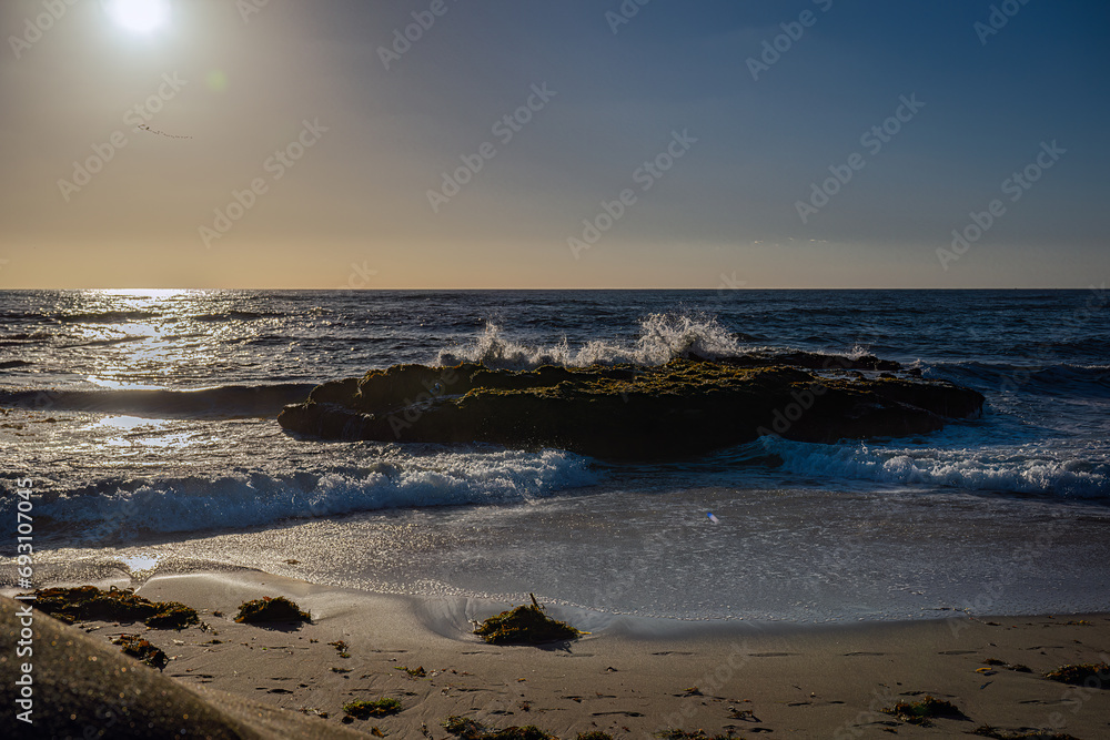 2023-12-14 A BACKLIT WAVE CRASHING ON THE SHORE OF A SMALL SAND BEACH IN LA JOLLA CALIFORNIA WITH A BRIGHT SUN REFLECTING OFF THE WATER